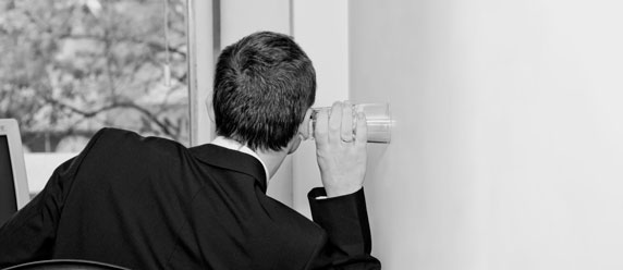 man listening through wall with a glass